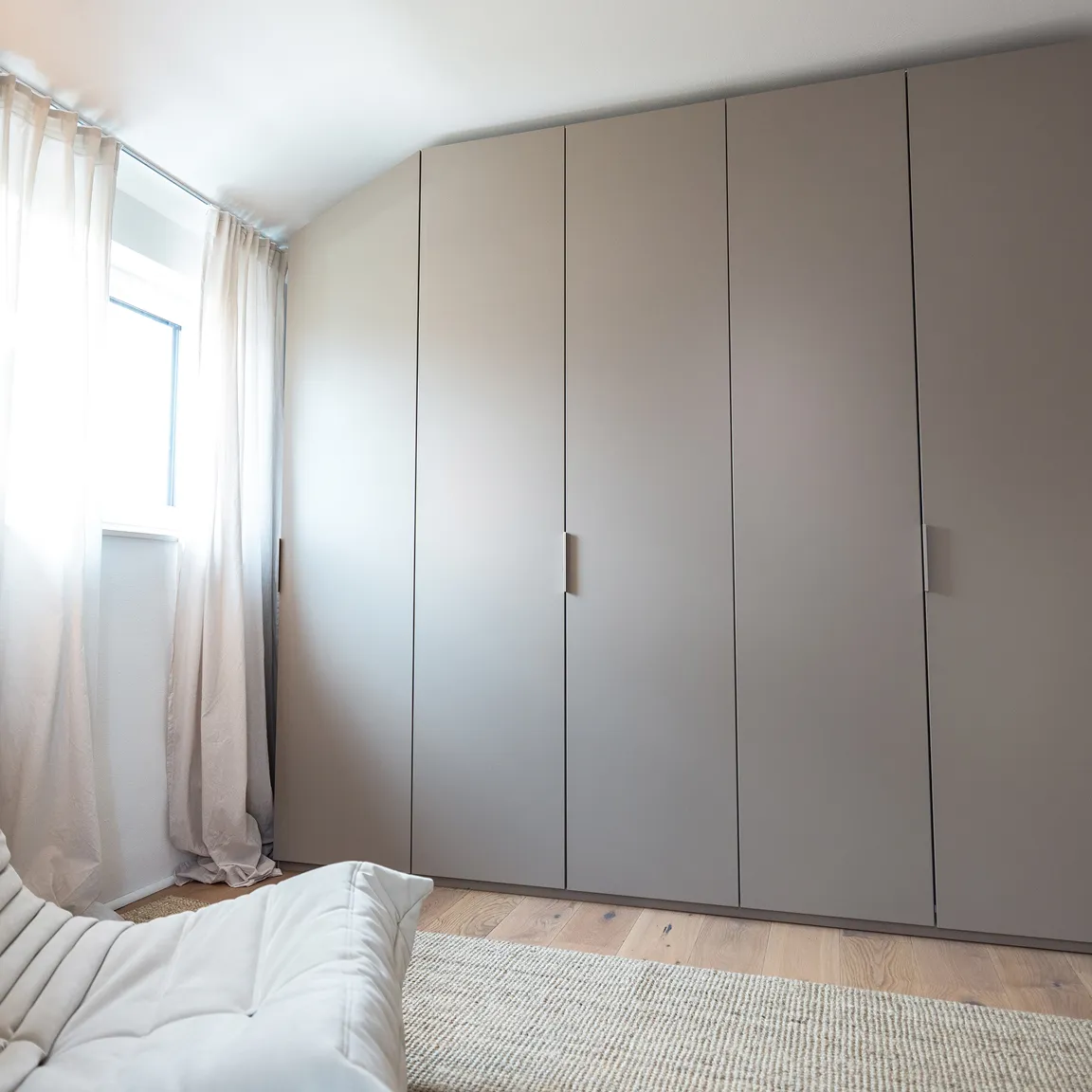 Grauer Kleiderschrank mit glatten Fronten im modernen Raum.